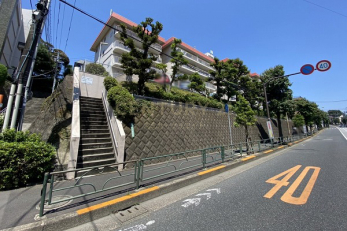 現地外観写真　建物外観（2022.6撮影）／「成城学園前」駅徒歩13分、野川にほど近い高台に立地、前面の世田谷通りに渋谷方向のバス停があります。